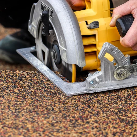 La sega circolare portatile, con una lama a denti grandi per il legno, taglia la lastra per terrazza in granulato di gomma WARCO in modo preciso lungo una linea.