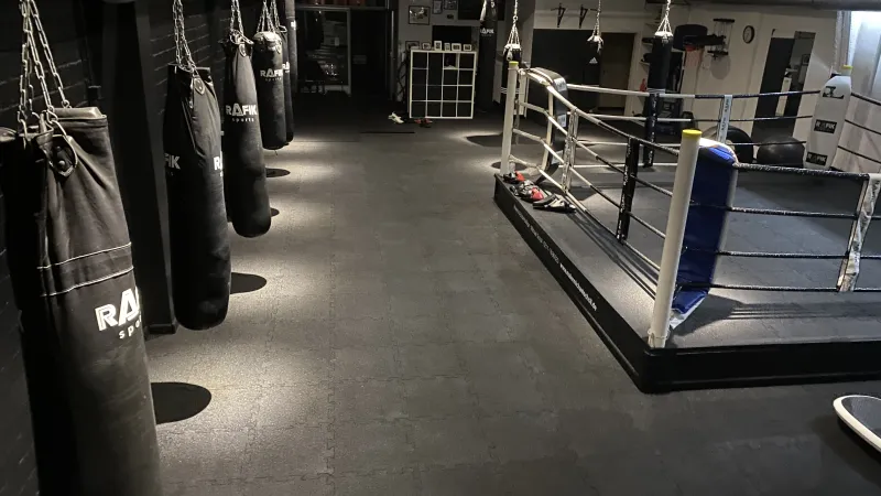 Gymboden mit Boxring und Boxsäcken für intensives Training.