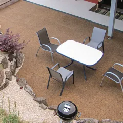 Die Terrasse aus braun-beige marmorierten Gummigranulatplatten von WARCO fügt sich harmonisch in die naturnahe Gartengestaltung ein. Der elastische Bodenbelag ist wetterfest und bietet auch barfuß ein angenehmes Laufgefühl. Der großzügige Sitzbereich mit Gartentisch und Stühlen lädt zum Verweilen ein. Der angrenzende Teich mit Natursteinen und üppiger Bepflanzung schafft eine idyllische Atmosphäre. Der runde Grill ergänzt die gemütliche Outdoor-Oase.
