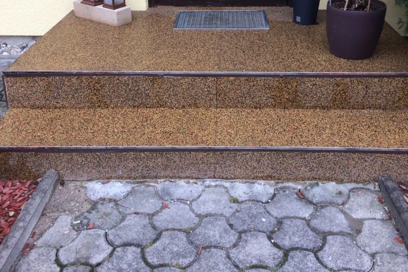 L'ingresso di una casa è stato parzialmente ristrutturato. Le scale sono rivestite con il pavimento elastico e antiscivolo WARCO. Il sentiero che conduce alla casa è pavimentato in cemento.