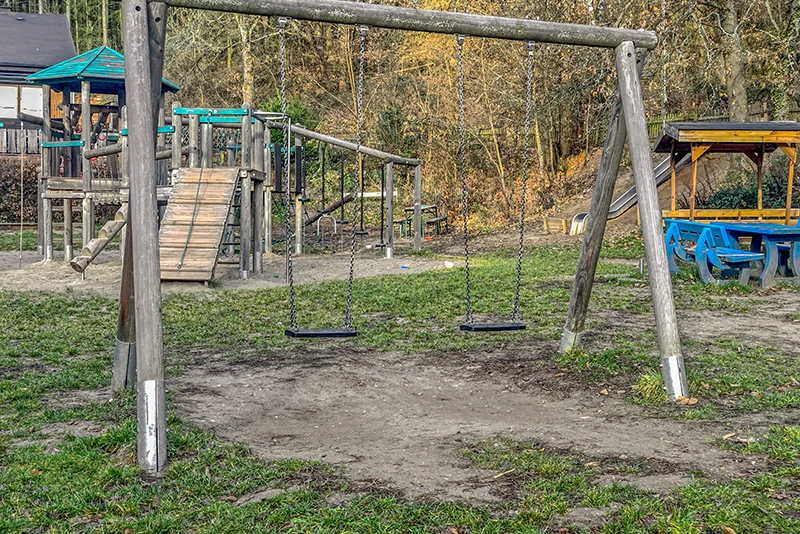 Un pavimento ricoperto d'erba non è adatto come protezione anticaduta in un parco giochi pubblico. L'erba sotto l’altalena per bambini è danneggiata.