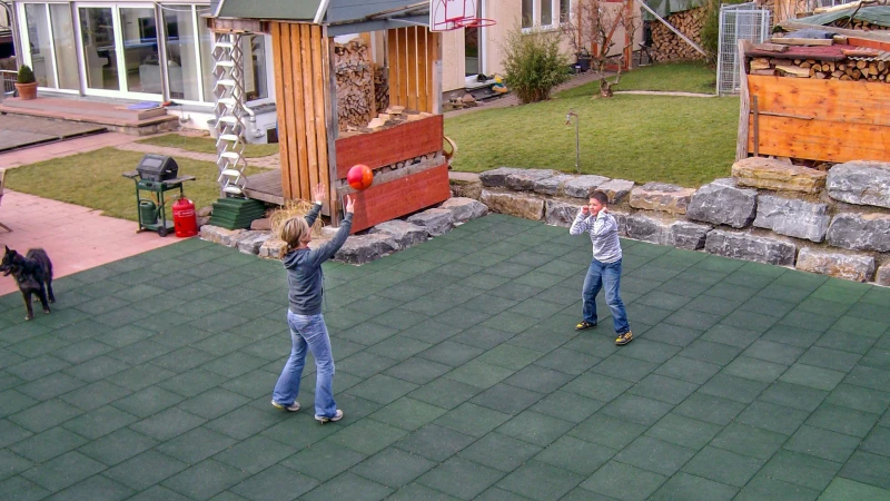 Una donna e un ragazzo giocano a pallavolo in un campo da gioco realizzato con le lastre WARCO verdi nel loro giardino privato. Qualunque sia il tempo, il campo è aperto a tutti i tipi di utilizzo sportivo.