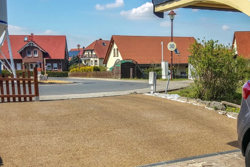 Un accesso al garage sul lato strada realizzato con lastre per marciapiede Pro WARCO in colore Caffè latte che si adattano bene al substrato anche se è in pendenza.
