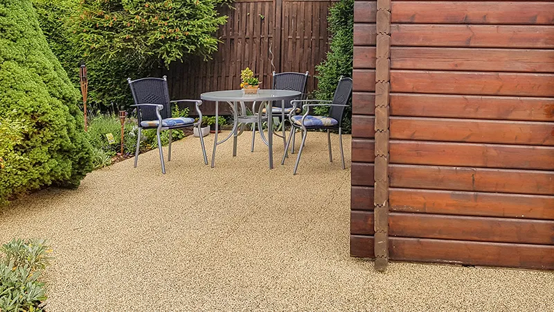 Die Terrasse eines Ferienhauses fügt sich durch die natürlich wirkenden beige-braunen Terrassenplatten ideal in die Umgebung ein und schafft eine harmonische Verbindung zwischen Ferienhaus und Garten. In der Fläche ist die Puzzleverzahnung an den Plattenrändern durch das strukturierte Farbdesign kaum sichtbar. Die Puzzleverzahnung verbindet die einzelnen Platten zu einer lagestabilen Plattenfläche. Daher wird dieser Terrassenbelag nicht mit dem Untergrund verklebt oder verschraubt. Die trittelastischen, vollflächig wasserdurchlässigen und rutschhemmenden Terrassenplatten isolieren gegen Bodenkälte und bieten Komfort zu jeder Jahreszeit.