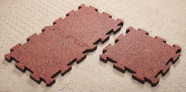 La posa dei tappeti antitrauma tipo puzzle di WARCO con la chiusura lampo formata sul strato di base di griglie di stabilizzazione in plastica.